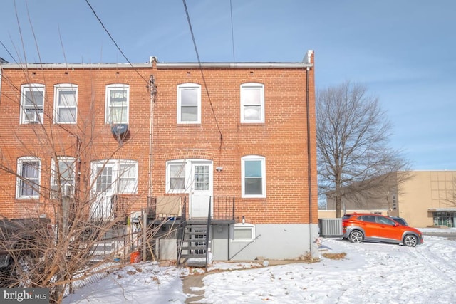 snow covered back of property with central AC