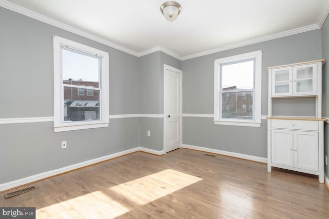 empty room with ornamental molding and light wood-type flooring