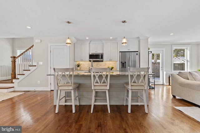 kitchen featuring decorative light fixtures, white cabinets, light stone counters, and appliances with stainless steel finishes