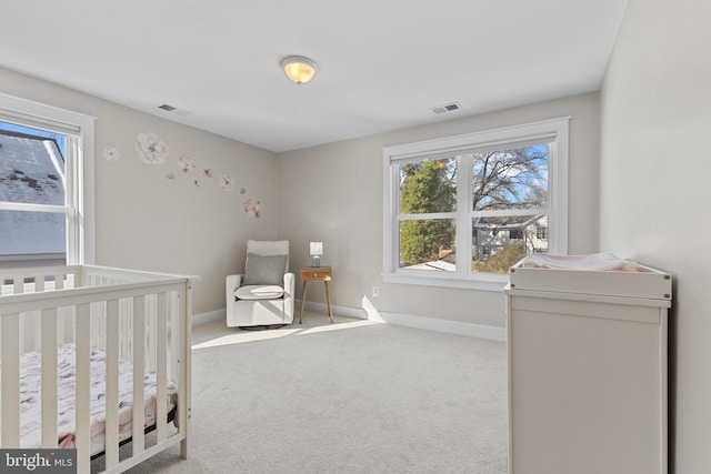 bedroom featuring a nursery area, light carpet, and multiple windows