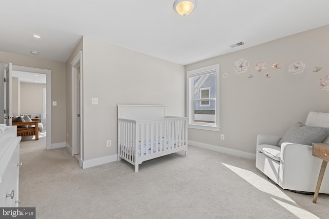 carpeted bedroom featuring a nursery area