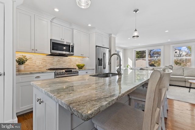 kitchen featuring white cabinets, appliances with stainless steel finishes, a kitchen island with sink, and sink