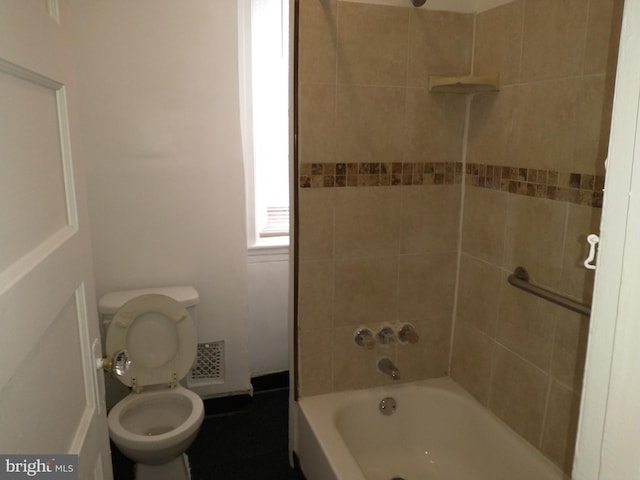 bathroom with tiled shower / bath combo and toilet