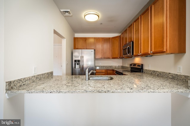 kitchen with kitchen peninsula, stainless steel appliances, light stone counters, and sink