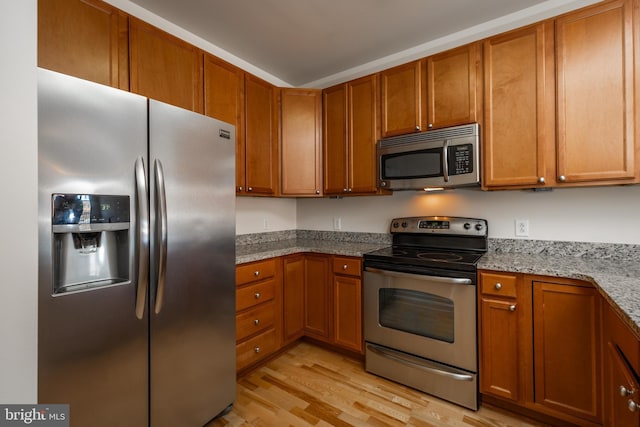 kitchen featuring light hardwood / wood-style floors, light stone countertops, and appliances with stainless steel finishes