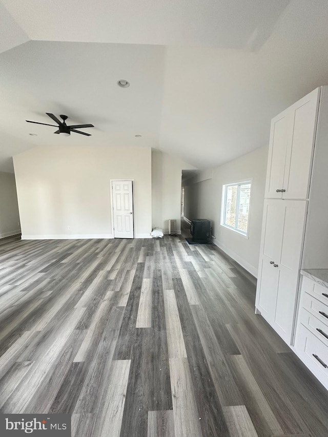 unfurnished living room with ceiling fan, lofted ceiling, radiator, and dark hardwood / wood-style flooring