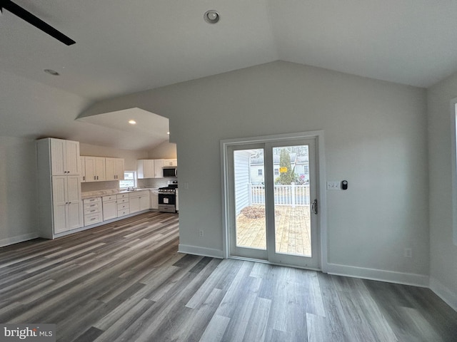 unfurnished living room featuring lofted ceiling, plenty of natural light, and wood-type flooring