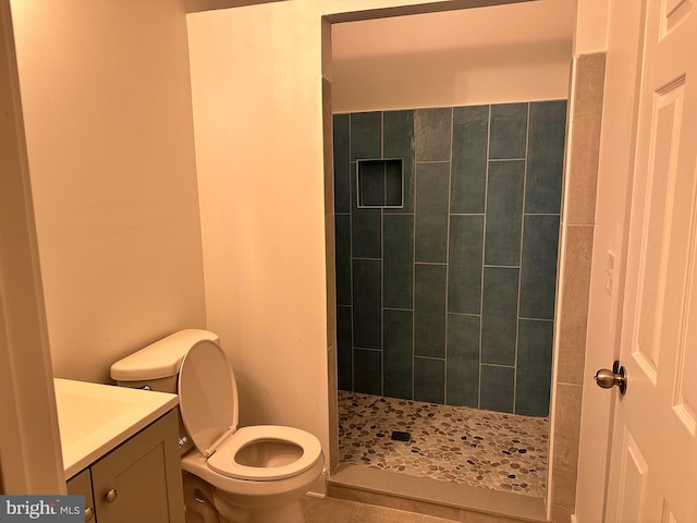 bathroom with vanity, toilet, and tiled shower