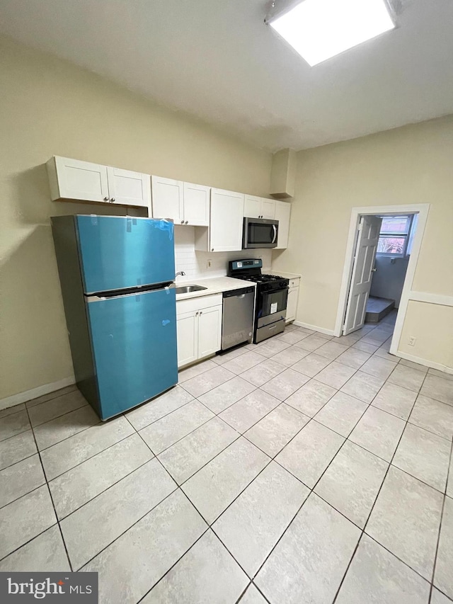 kitchen with white cabinets, sink, light tile patterned floors, and stainless steel appliances