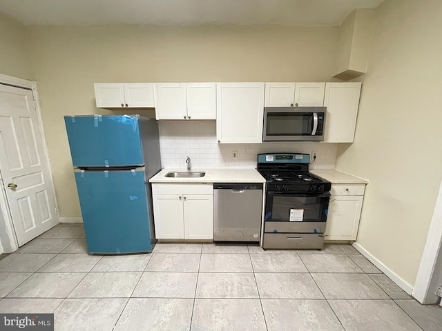 kitchen featuring decorative backsplash, stainless steel appliances, sink, light tile patterned floors, and white cabinets