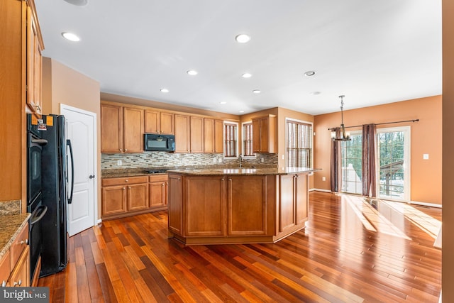 kitchen with black appliances, hanging light fixtures, a notable chandelier, dark hardwood / wood-style flooring, and decorative backsplash