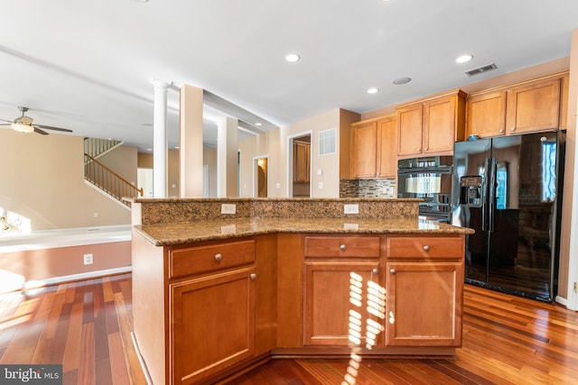 kitchen featuring wood-type flooring, a center island, backsplash, and black appliances