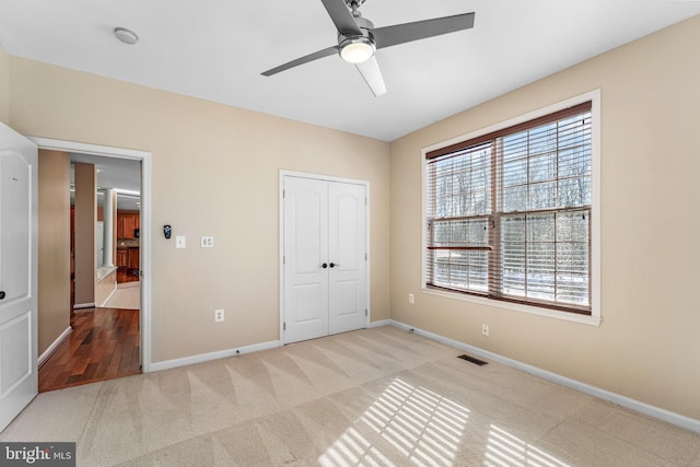 unfurnished bedroom with light colored carpet, ceiling fan, and a closet