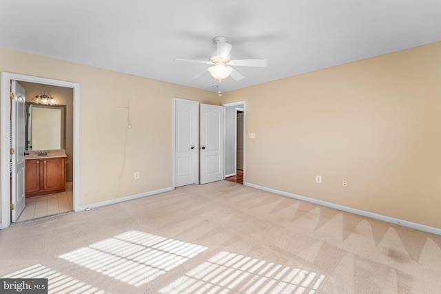 unfurnished bedroom with ensuite bathroom, ceiling fan, and light carpet