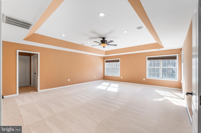 spare room featuring ceiling fan, a raised ceiling, and light carpet