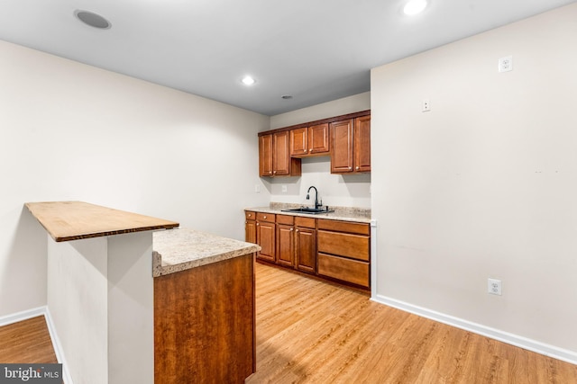 kitchen with sink, light wood-type flooring, and kitchen peninsula