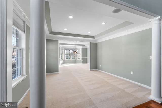 carpeted spare room featuring ornate columns, ornamental molding, and a tray ceiling