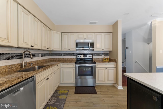 kitchen with light stone countertops, appliances with stainless steel finishes, decorative backsplash, and sink