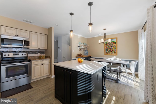 kitchen featuring backsplash, appliances with stainless steel finishes, light hardwood / wood-style flooring, and hanging light fixtures