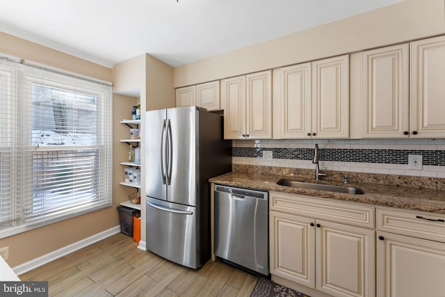 kitchen featuring appliances with stainless steel finishes, dark stone countertops, cream cabinetry, and sink