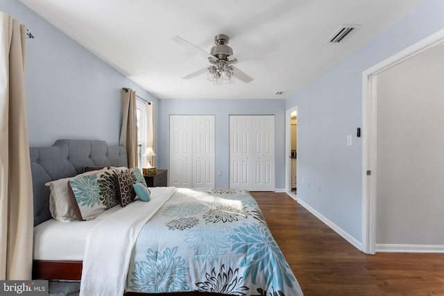 bedroom featuring dark wood-type flooring, ceiling fan, and multiple closets