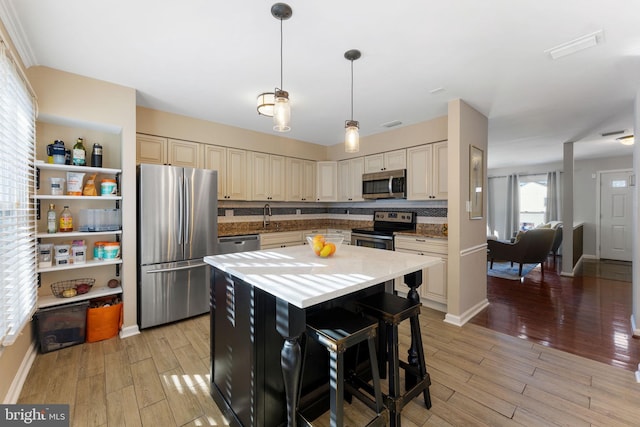 kitchen featuring appliances with stainless steel finishes, a breakfast bar, pendant lighting, a kitchen island, and decorative backsplash