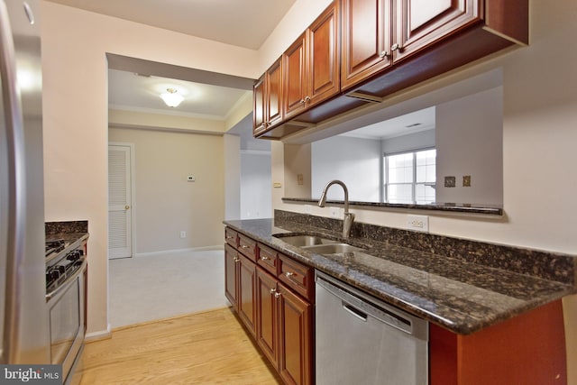 kitchen featuring sink, light hardwood / wood-style flooring, dark stone counters, appliances with stainless steel finishes, and ornamental molding