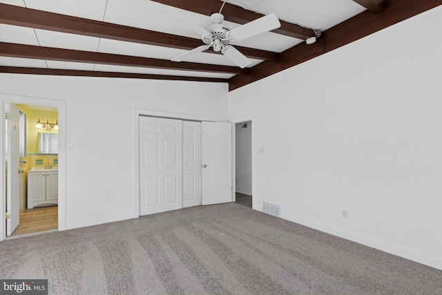 unfurnished bedroom featuring ceiling fan, light carpet, vaulted ceiling with beams, and connected bathroom