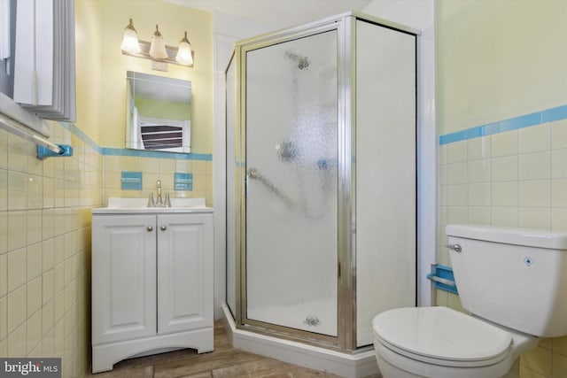 bathroom with toilet, vanity, tile walls, hardwood / wood-style flooring, and an enclosed shower