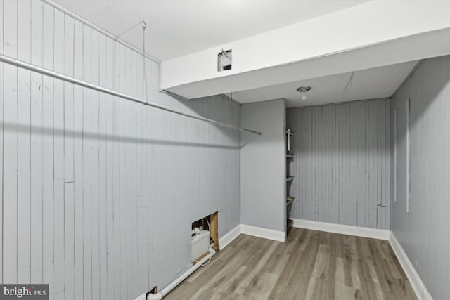 clothes washing area with hookup for a washing machine, hardwood / wood-style floors, wooden walls, and a fireplace