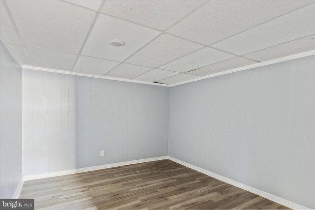 empty room with a drop ceiling and hardwood / wood-style floors