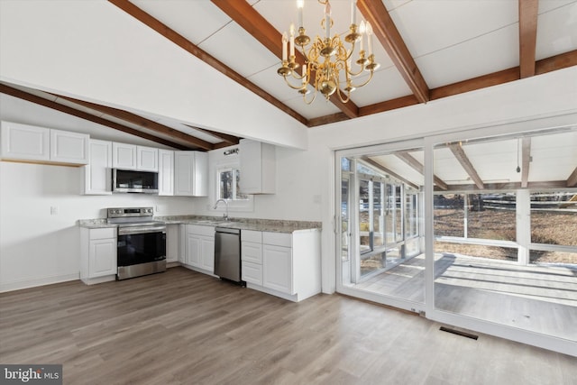 kitchen with appliances with stainless steel finishes, pendant lighting, white cabinets, an inviting chandelier, and sink