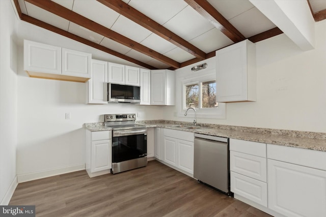 kitchen featuring dark wood-type flooring, light stone countertops, white cabinetry, appliances with stainless steel finishes, and sink