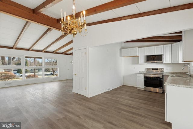 kitchen with stainless steel appliances, lofted ceiling with beams, white cabinetry, and sink