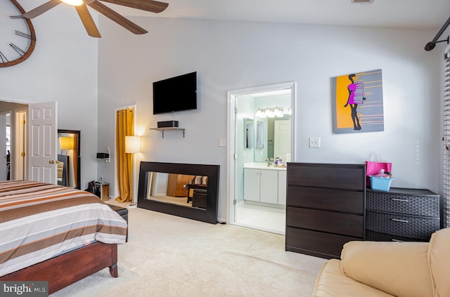 carpeted bedroom featuring ceiling fan, ensuite bathroom, and high vaulted ceiling