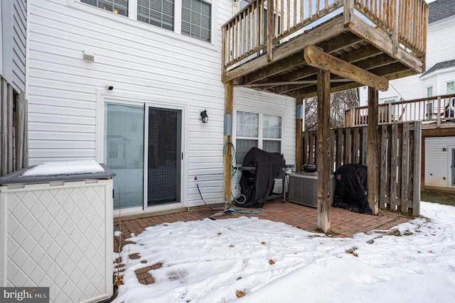 snow covered patio with a wooden deck