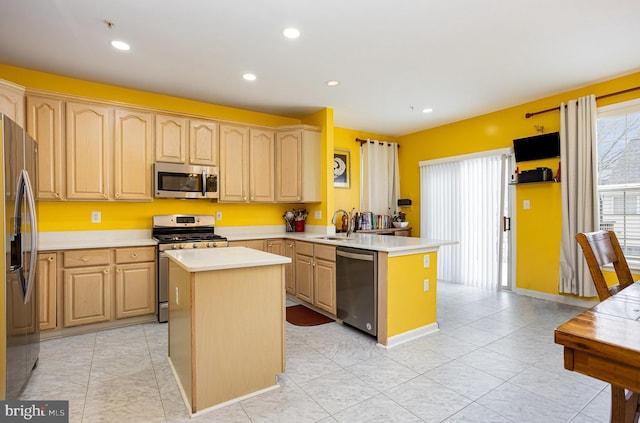 kitchen featuring kitchen peninsula, light brown cabinets, stainless steel appliances, and a kitchen island