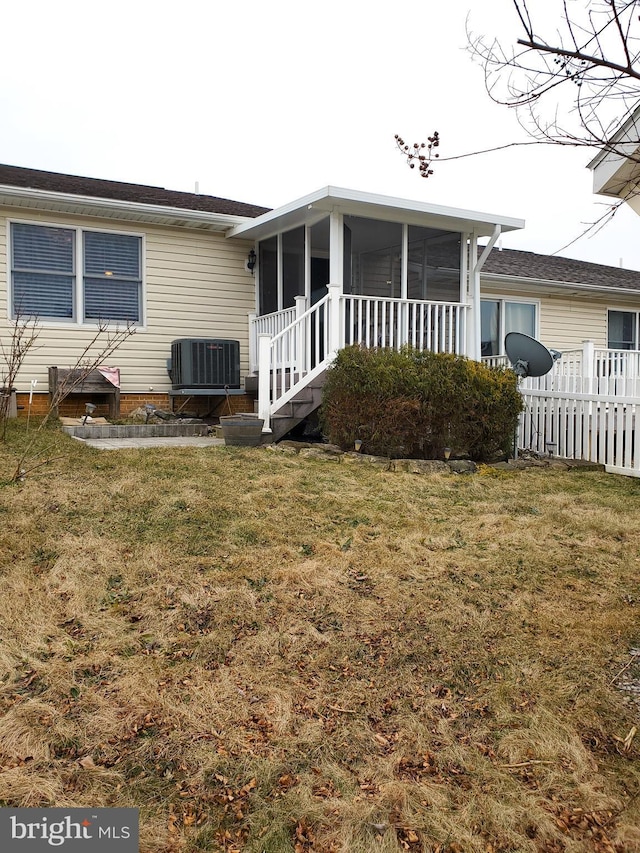 rear view of property featuring cooling unit, a yard, and a sunroom