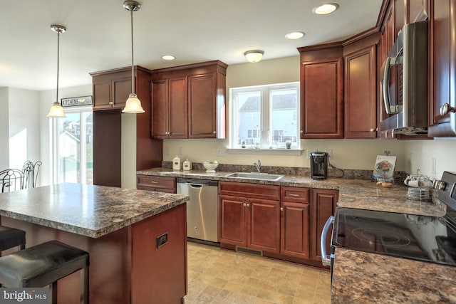 kitchen featuring sink, a kitchen breakfast bar, pendant lighting, and appliances with stainless steel finishes