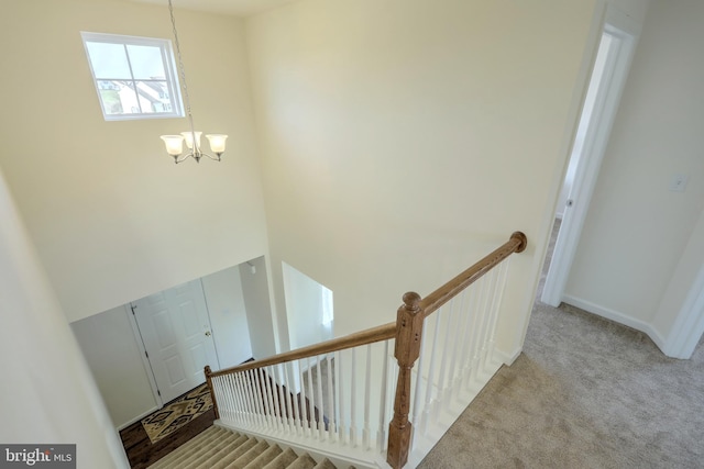 staircase featuring carpet floors and a chandelier