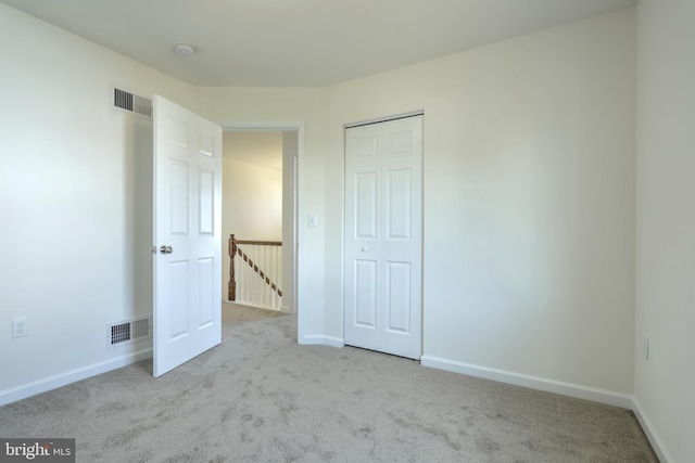 unfurnished bedroom with a closet and light colored carpet