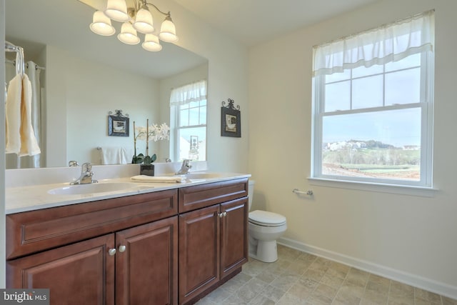 bathroom featuring toilet, vanity, an inviting chandelier, and plenty of natural light