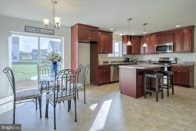 kitchen featuring decorative light fixtures, an inviting chandelier, appliances with stainless steel finishes, and a center island