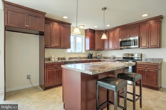 kitchen with stainless steel appliances, sink, a kitchen breakfast bar, a kitchen island, and pendant lighting