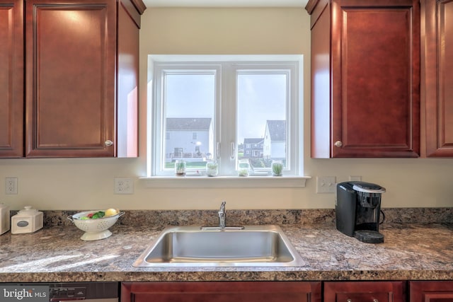 kitchen with dark stone counters, dishwasher, and sink