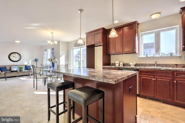 kitchen featuring sink, a breakfast bar area, a kitchen island, pendant lighting, and a notable chandelier