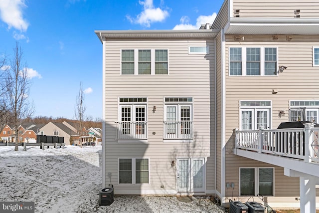 snow covered rear of property featuring central AC