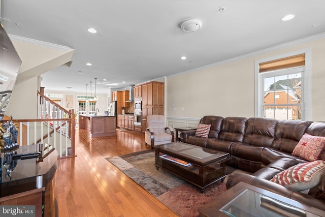 living room with sink, crown molding, and light wood-type flooring