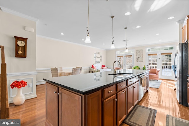 kitchen with sink, hanging light fixtures, a center island with sink, and ornamental molding