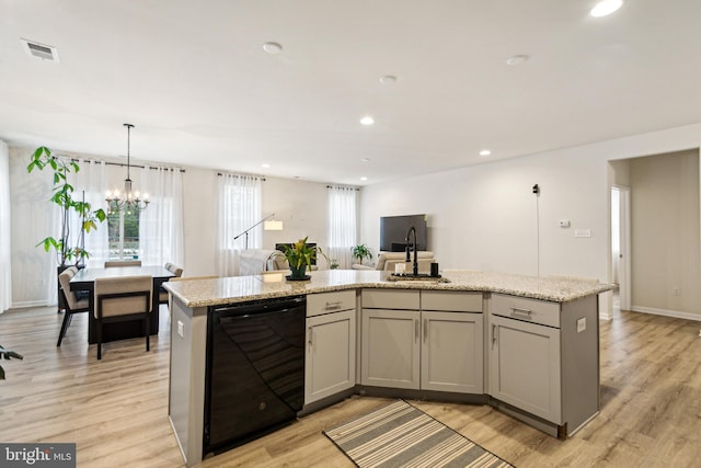 kitchen with pendant lighting, dishwasher, and a center island with sink